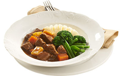 Beef stew served with mash and steamed green vegetables